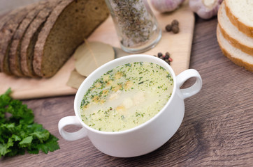 Mushroom soup with croutons in a white dish is on a wooden table.