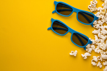 new 3d glasses and popcorn on a yellow. Сoncept of cinema background