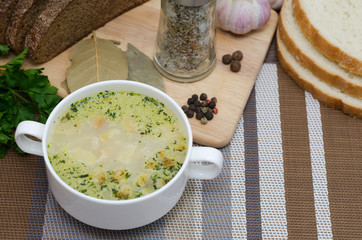 Mushroom soup with croutons in a white dish is on a wooden table.