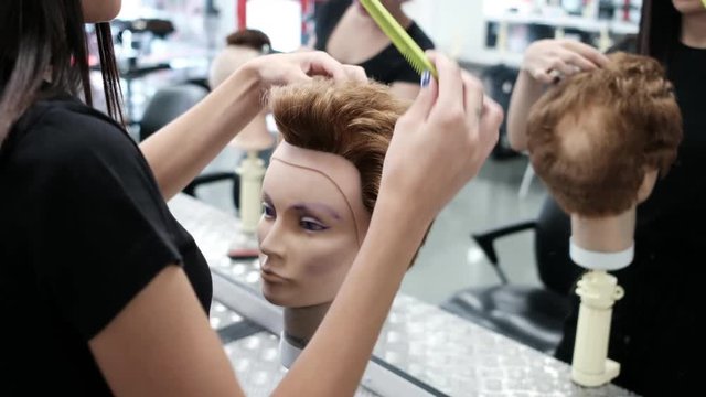 Woman training hairdressing with mannequin head in hair salon