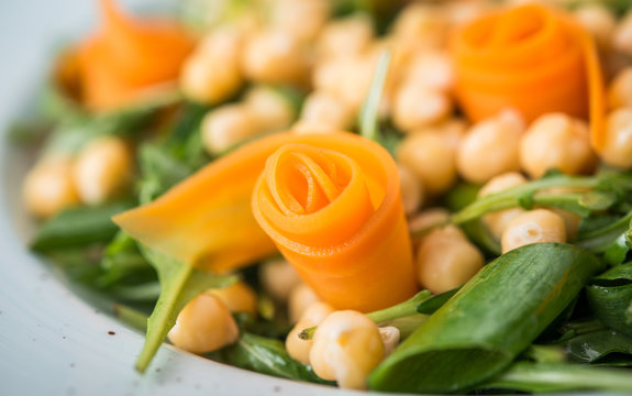 Flower decoration made of carrot in vegan salad, close up