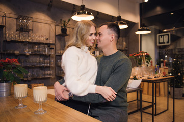 A couple is sitting in the cafe on Valentine's day. The woman is hugging her boyfriend. They are on a date. The atmosphere of love in the air.