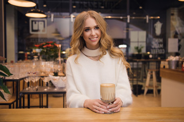 A young woman is waiting for her boyfriend. Valentine's day. She's drinking coffee.