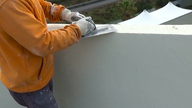 Construction worker plastering a wall with American trowel in hand