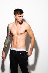 Obraz premium Muscular beautiful sexy guy with tattoos on body posing, isolated on white