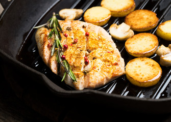 chicken fillet fried and potatoes in a frying pan