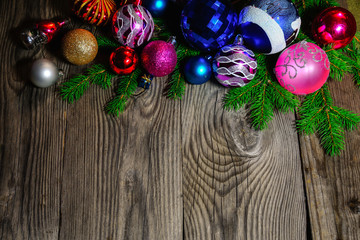 Christmas balls lie on fir branches on a wooden background