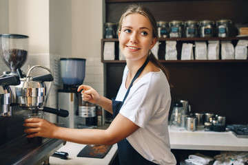 Portrait of happy beautiful young Caucasian smiling woman barista holding plastic cup with ice. Server making cold drink in coffee shop. Small business owner and person at work concept.