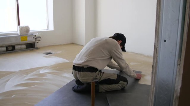 Worker with four hands makes repairs smears on wall putty. Artisan repairs the shutters of an outdoor home with a grinder that makes red and yellow sparks. Builder makes the eaves of the roof