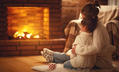 Fotobehang family mother and child hugs and warm on winter evening by fireplace. © JenkoAtaman