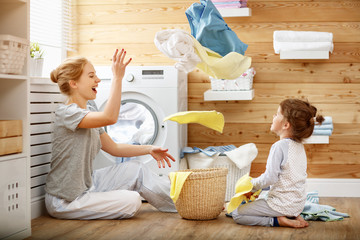 Happy family mother housewife and child   in laundry with washing machine
