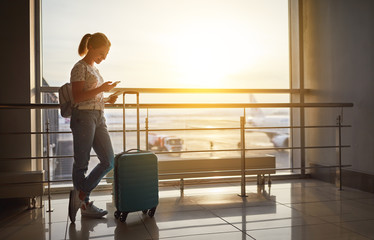 young woman waiting for flying at airport at window with suitcase  .