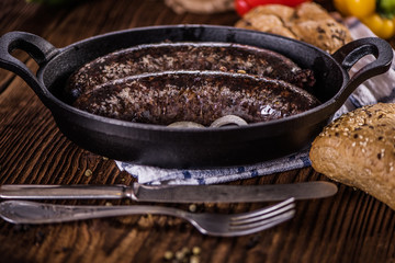 blood sausage in black cast iron baking pot on wooden table 