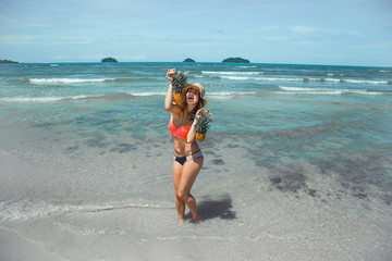 beautiful girl with pineapple on an exotic beach, a happy mood and a beautiful smile, top view