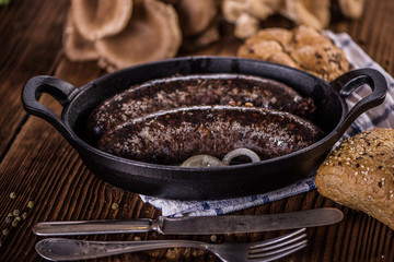 blood sausage in black cast iron baking pot on wooden table 
