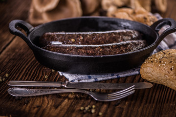 blood sausage in black cast iron baking pot on wooden table 