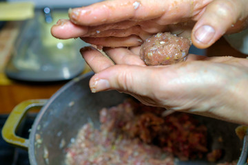 Human hands make meatballs from raw minced meat. The concept of natural cooking. Close-up.