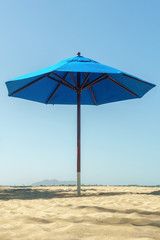 open blue beach umbrella with shadow on the sandy beach