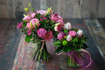 Rustic wedding bouquets for bride and bridesmaid, made with roses, carnations, daisies, tulips and Lisianthus flowers in different shades of pink.