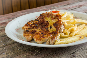 Chicken thigh with French fries on a wooden background. chicken thigh on a plate. rustic food