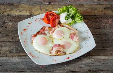 Eggs and bacon with tomato for breakfast. On a wooden background. Top view. rustic food