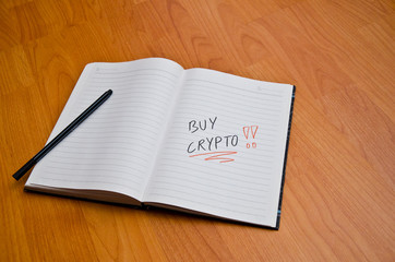 Notebook and marker with handwritten "Buy Crypto" note