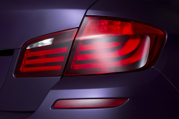 Car rear lights with matte surface, red backlights of lilac powerful sport sedan bodywork, concept 