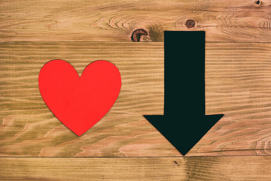 Red heart and arrow going down on wooden table,relationship breakup concept.