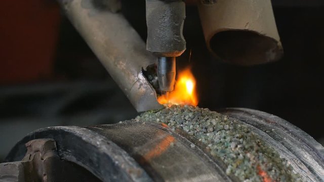 Close up of welding robots apply overlay weld protection on the pipe disks. Automatic welding of pipe-rolling