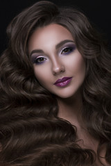 Fototapeta premium Piękna dziewczyna kaukaski z długimi falującymi i lśniącymi włosami. Brunetka kobieta z kędzierzawą fryzurą