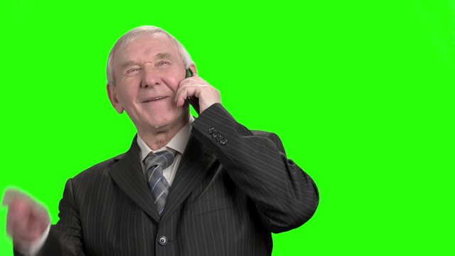 Cheerful old politician talking on phone. Happy senior politition talking on phone with his family and laughing, green hroma background.