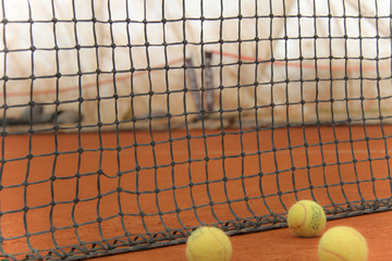 Tennis balls on red court with gray net