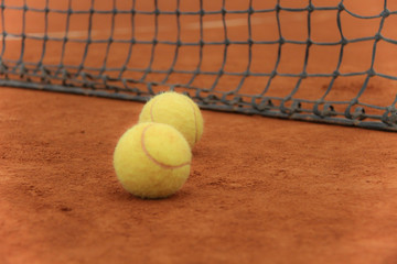 Tennis balls on red court with gray net