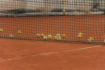 Tennis balls on red court with gray net