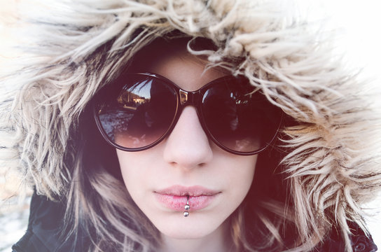 Young woman with winter hood and sunglasses