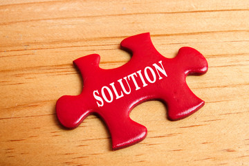 Missing red jigsaw puzzle on wooden tablewith word SOLUTION.