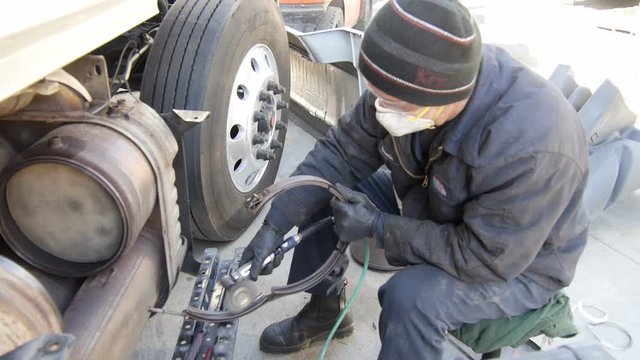 Mechanic working on diesel semi truck engine in garage repair shop