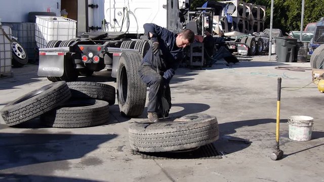 Mechanic working on semi truck tires in repair shop garage