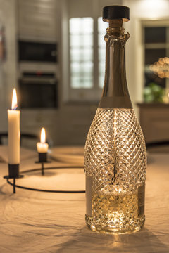 En flaska mousserat vin med st&auml;mnings ljus i bakgrunden