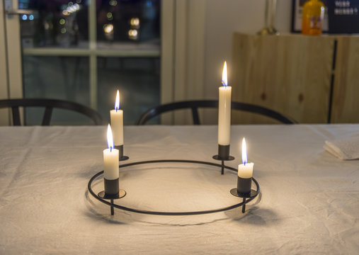 Rund julljusstake lyser med sina fyra t&auml;nda ljus p&aring; julbordet