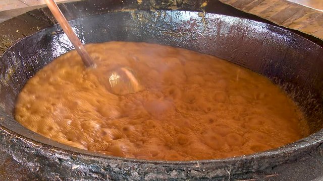 Man stirs a vat of boiling caramelized sugar