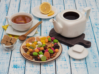 Cup of tea with lemon, a teapot and dried fruits on a wooden table
