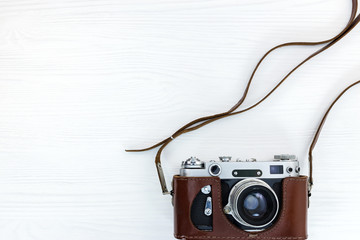 vintage photo camera in brown leather case on white wooden background
