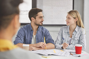 Female and male colleagues have conversation during working process, discuss marketing seminar,...