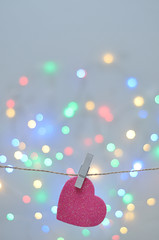A pink heart shape hanging on a rope with an out of focus light background