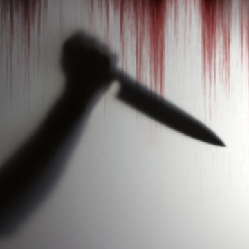 Shadow of hand holding knife to pierce the victim behind a transparent object with bloody background scary