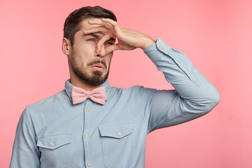 Displeased brunet male plugs nose as smells something stink and unpleasant, feels aversion,...