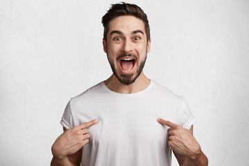 Excited young handsome male brunet with trendy hairdo, mustache and beard, happy to buy new...