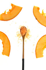 Salt  with pumpkin extract . orange sea salt in a wooden spoon and pieces of fresh pumpkin on a white background. organic beauty