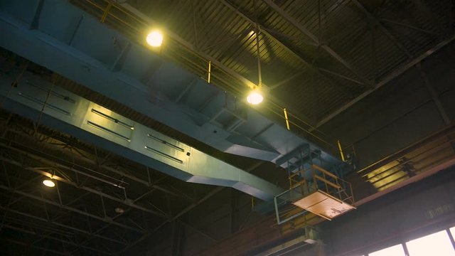 Heavy bridge crane with hook moving alongside the factory